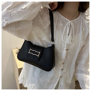 Gros plan du sac sous le bras noir minimaliste avec boucle dorée porté par un mannequin