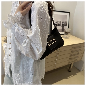 Gros plan d'un sac d'épaule en cuir noir avec une boucle dorée élégante