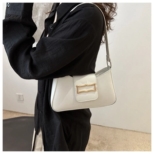 Détail d'un sac à bandoulière en cuir blanc avec boucle décorative géométrique dorée