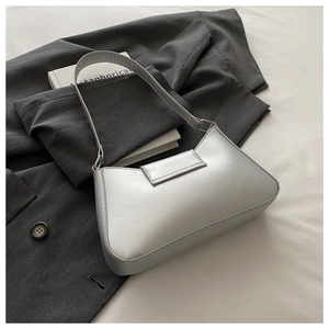 Détail d'un sac à bandoulière argenté métallisé avec boucles élégantes sur un tissu doux