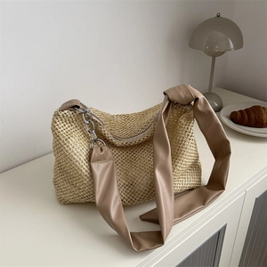 Woven straw tote bag with brown faux leather shoulder strap and silver chain details
