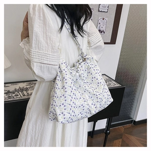 Floral tote bag with purple tulip pattern and drawstring closure shown on shoulder