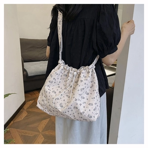 Floral drawstring shoulder bag in cream with blue flower patterns and wide strap