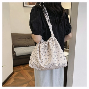 Detail of the blue floral pattern and soft drawstring on the cream shoulder bag