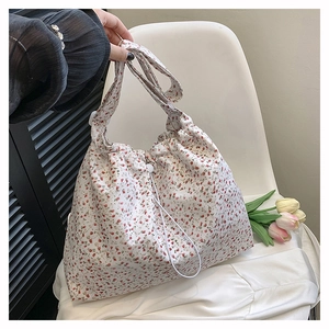 Detail of floral drawstring tote bag with pink patterns on beige canvas and drawstring close
