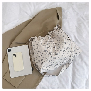 Detailed view of floral canvas tote bag with drawstring closure and wide shoulder strap