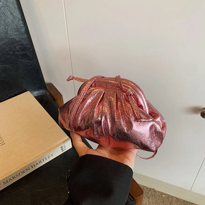 Metallic pink pleated cloud bag with slim shoulder strap displayed on a modern chair