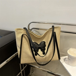 Beige woven straw tote bag with black leather butterfly patch and twin shoulder straps
