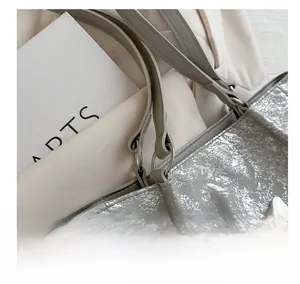 Détail du charm papillon argenté et du connecteur d'anneau sur le sac fourre-tout