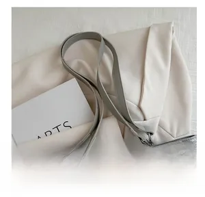 Détail du sac cabas argenté montrant les anses en cuir et les anneaux métalliques