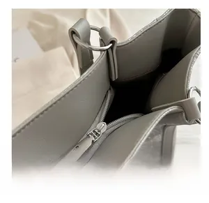 Détail de la fermeture à glissière en métal argenté sur un sac cabas en cuir gris texturé