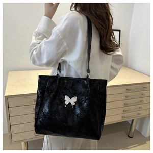 Détail du grand sac cabas noir avec papillon argenté et texture brillante lisse
