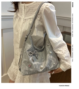 Detail of silver bucket bag with metallic texture, pearl accents, and rhinestone bow