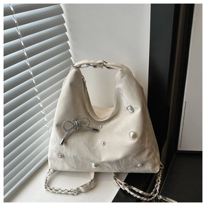 Close-up of cream hobo bag featuring rhinestone butterfly and pearl embellishments