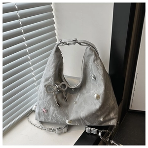 Detail of silver pleated bag with pearl embellishments and a rhinestone bow ornament