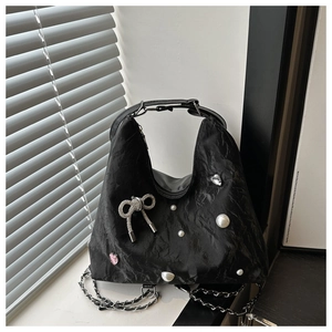 Detail of black pleated shoulder bag with pearl accents and rhinestone bow decoration