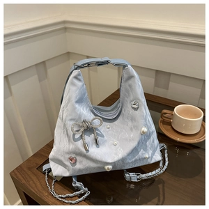Close-up of light blue pleated handbag with rhinestone bow and pearl decorations
