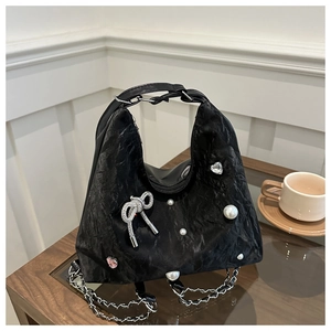 Detail of black pleated shoulder bag with pearl bow and rhinestone heart embellishments