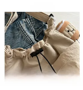 Dettaglio della borsa a secchiello in nylon beige con coulisse nera e fibbia a molla
