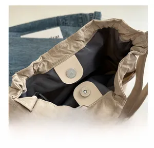 Dettaglio della chiusura magnetica in metallo su una borsa a secchiello in nylon beige