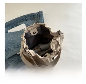 Dettagli interni che mostrano la grande capacità della borsa a secchiello beige con coulisse