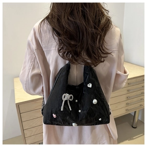 Rear view of black pleated hobo bag with pearl and rhinestone heart charms worn on shoulder