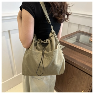 Detail of army green nylon drawstring bucket bag with large pocket on female model