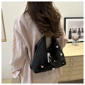 Detail of black pleated hobo bag featuring pearl accents and rhinestone bowtie charm