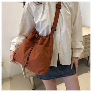 Detail of caramel nylon bucket bag with dual front pockets and adjustable strap