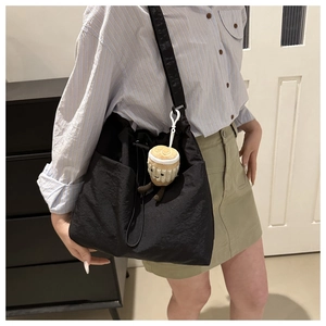 Detail of black nylon drawstring bucket bag with a cute plush coffee cup charm pendant