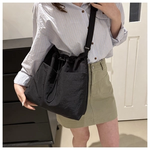 Close-up of black nylon bucket bag with drawstring closure and large front pockets