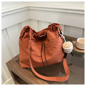 Detail of orange nylon bucket bag with drawstring closure and cute coffee cup plush charm