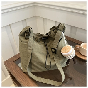 Detail of olive green tote bag with pleated fabric texture and cupcake bag charm