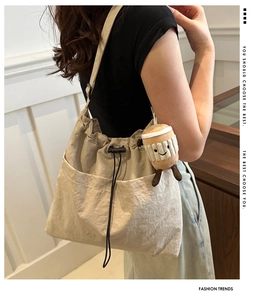Detail of a beige drawstring nylon bucket bag featuring a cute plush coffee cup charm
