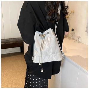 Detail view of silver bucket bag with golden butterfly clasp and pearl drawstring accents