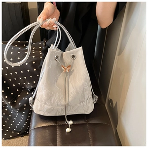 Detail of silver bucket bag with butterfly metal charm and pearl drawstring accents