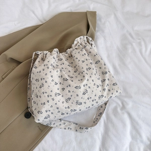 Floral canvas tote bag with drawstring closure laid on a khaki blazer jacket