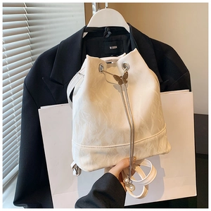 Close-up of white pleated bucket bag with gold butterfly clasp and pearl charm detail
