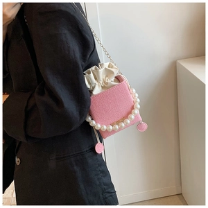 Pink woven bucket bag featuring elegant pearl handle and golden chain shoulder strap