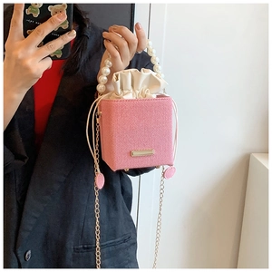 Pink bucket bag with luxury pearl handle, gold chain strap and drawstring lining detail