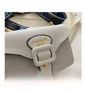 Detail of canvas crossbody bag with white buckle and navy blue lettered shoulder strap