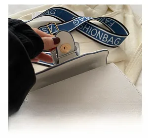 Detail showing high-quality golden magnetic buckle on white textured canvas flap bag