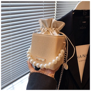 Detail of summer straw bucket bag with large pearl handle and gold chain strap