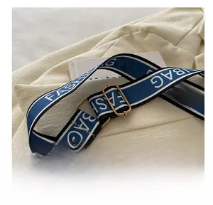 Detail of adjustable blue and white striped canvas strap with gold metal buckle