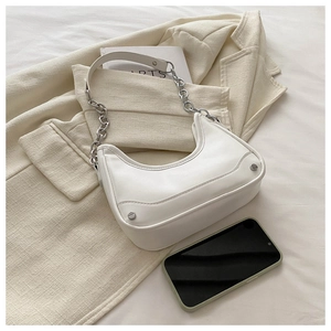 Detail of white moon-shaped hobo bag with silver chain strap and metal stud accents