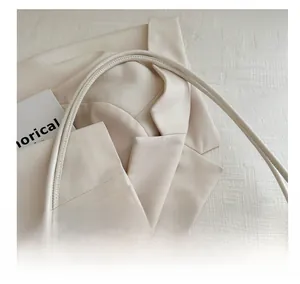 Detail of the slender handles on a cream beige tote bag with a premium smooth texture