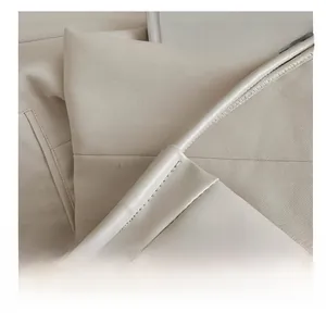 Macro shot of precise stitching on high-quality off-white leather shoulder tote bag