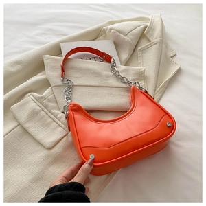 Detail of bright orange crescent bag with chunky silver chain and rivet accents