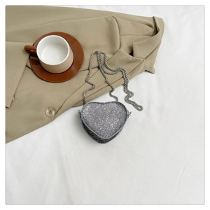 Detail of silver heart-shaped crossbody bag featuring sparkling rhinestones and chain strap