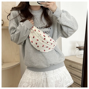 Dettaglio del marsupio in velluto beige con stampa fragola indossato da una modella
